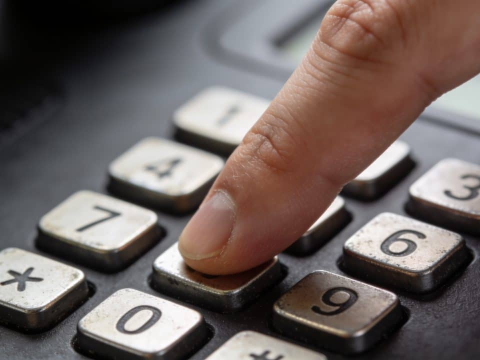 Doigt compose un numero sur clavier telephonique noir.