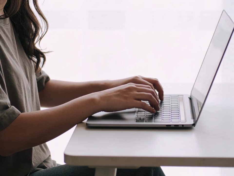 Femme assise au bureau tapant sur clavier d'ordinateur portable