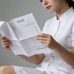 Femme en uniforme blanc consultant document salarial papier.