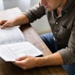 Homme consultando papeles de prestaciones sociales mensuales
