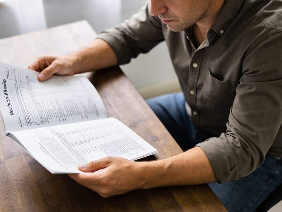 Homme consultando papeles de prestaciones sociales mensuales