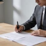 Homme en costume assis au bureau signataire contrat