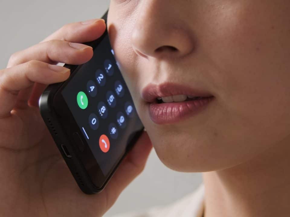 Telephone screen displaying incoming call number with person listening.