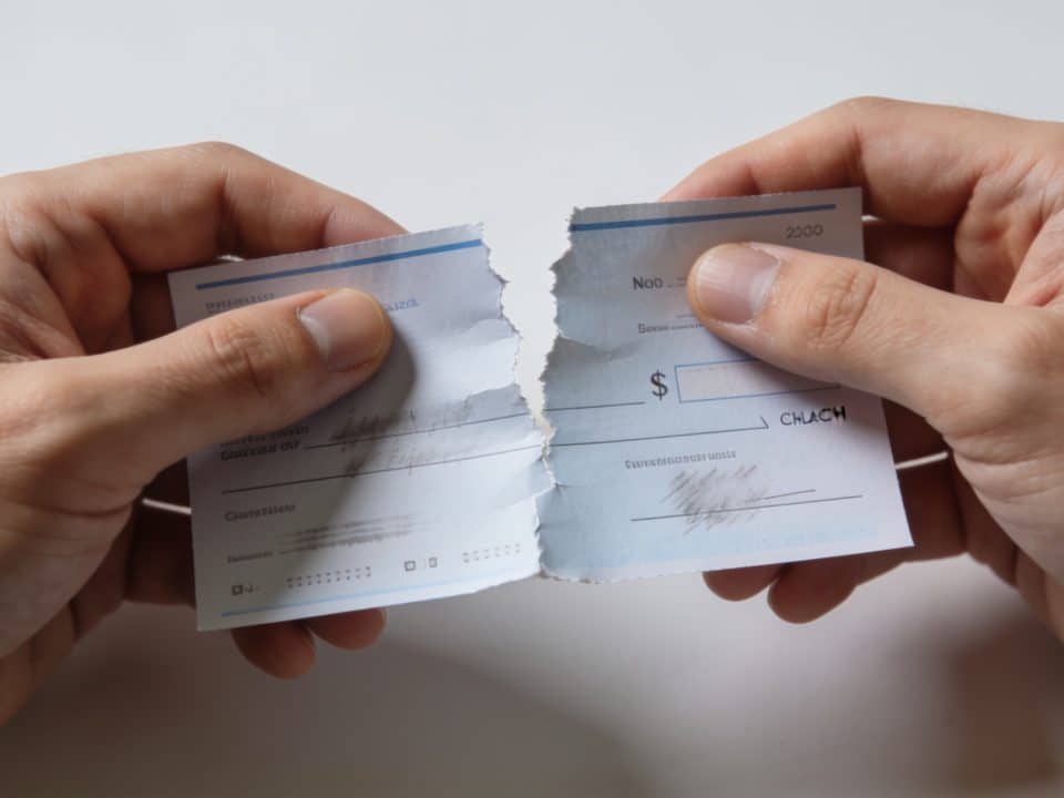 Mains tenant un cheque bancaire dechire ou suspect.