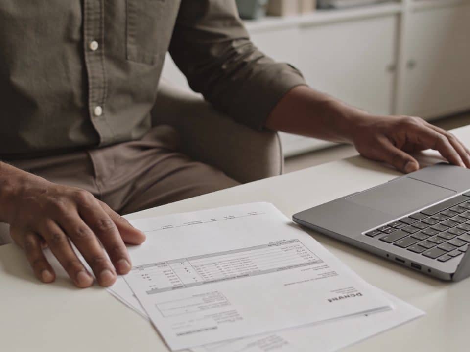 Personne assise devant ordinateur consultent documents financiers salaire
