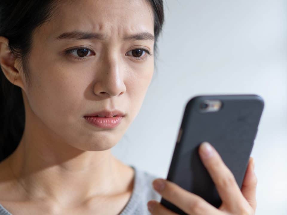 Personne tenant un téléphone avec expression préoccupée